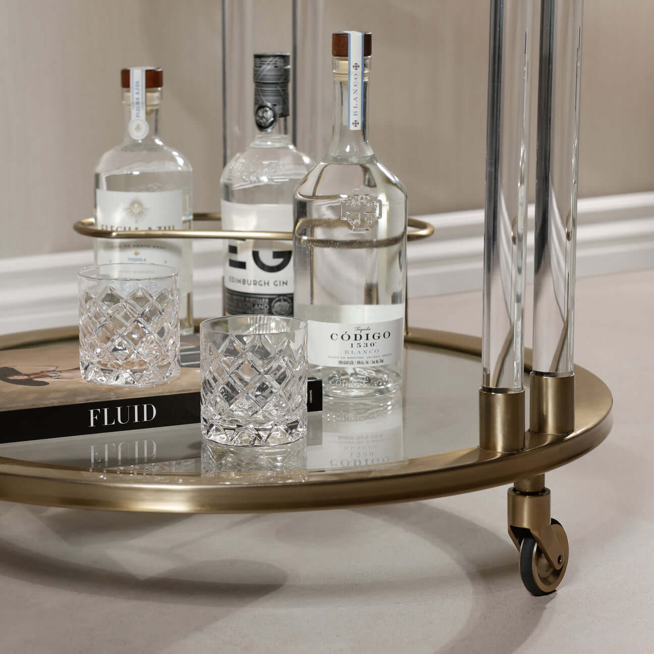 Opus Round Bar Cart / Trolley featuring a round mirrored top, acrylic legs, and elegant glassware.