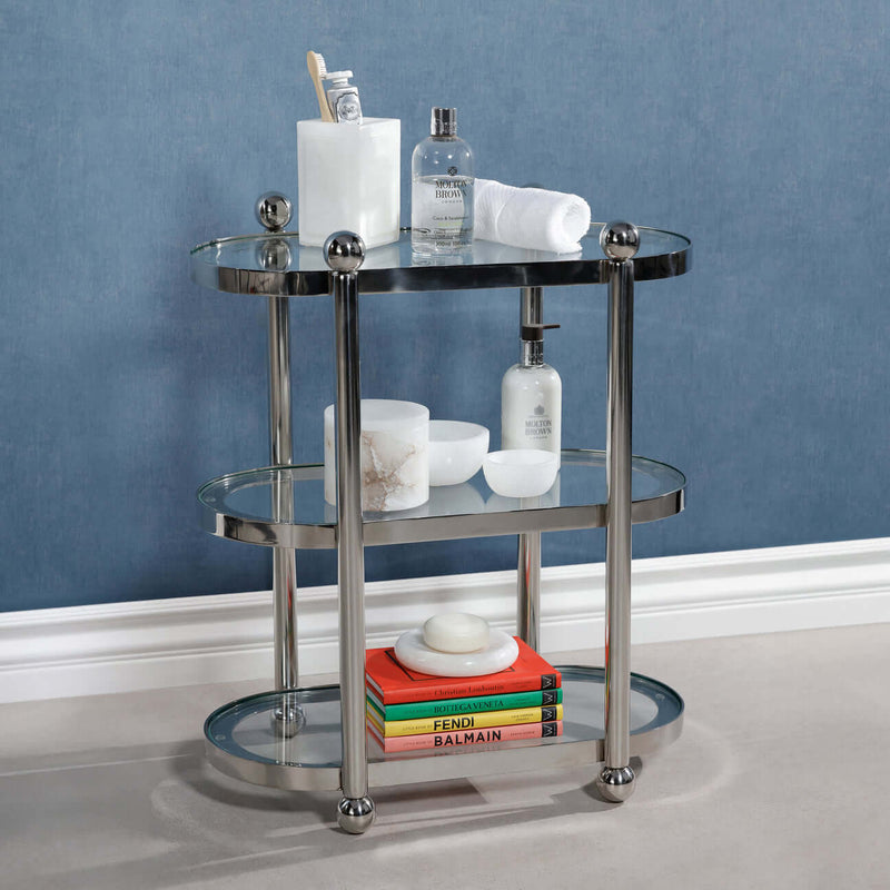 Three-Tier Étagère with a polished silver frame, displaying bath essentials and books on clear glass shelves.