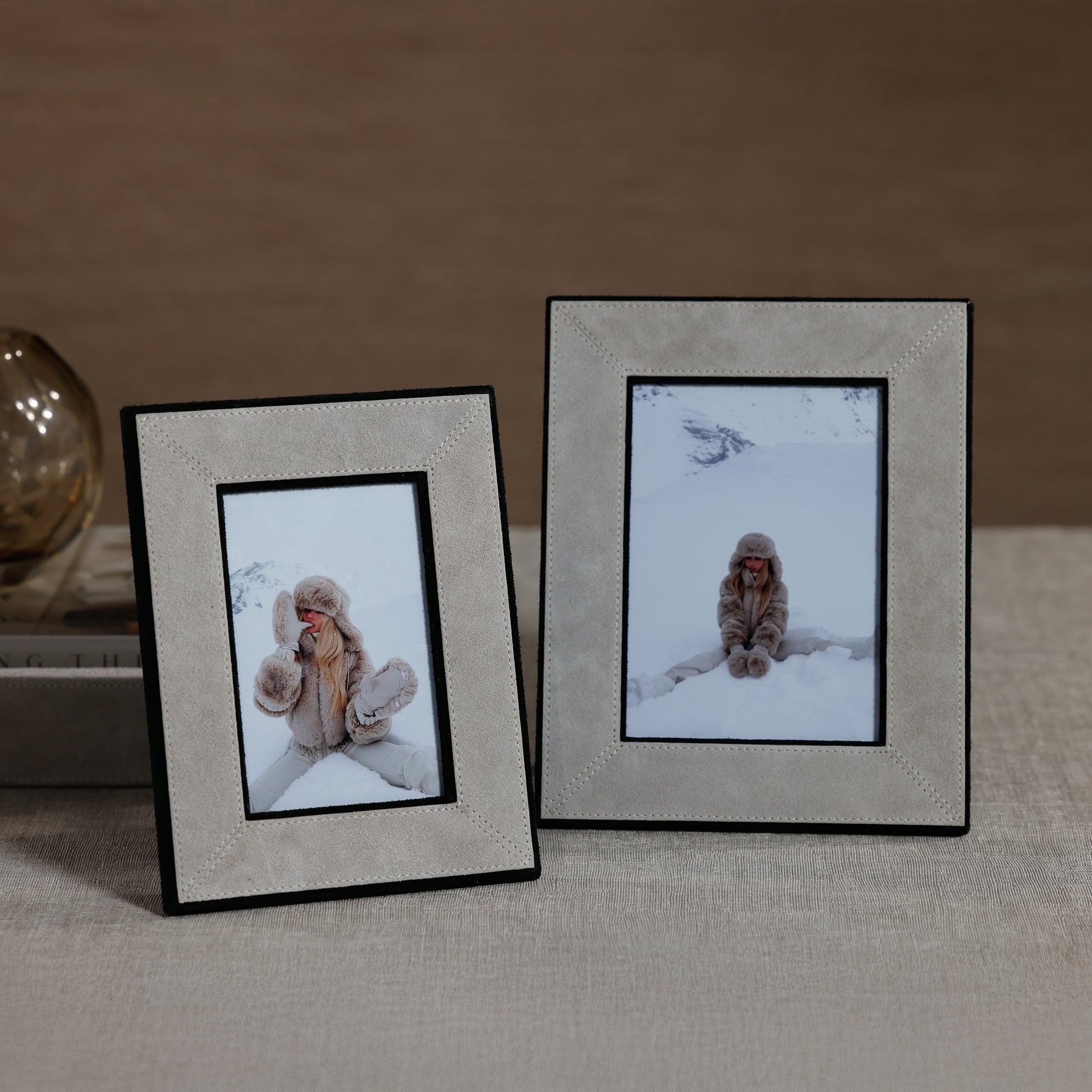 Two framed pictures of a person in a snowy landscape on a textured surface.