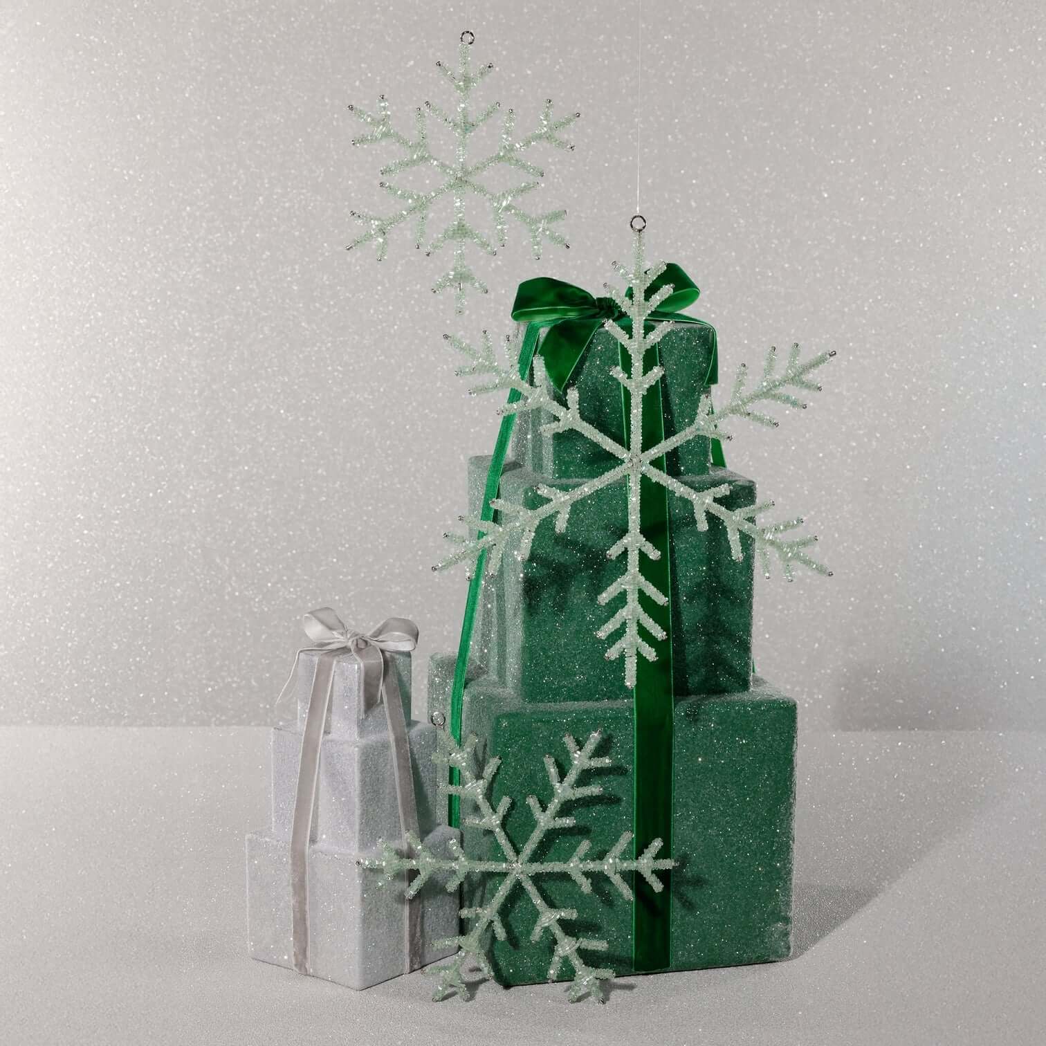 Green and silver gift boxes with snowflake decorations on a light gray background