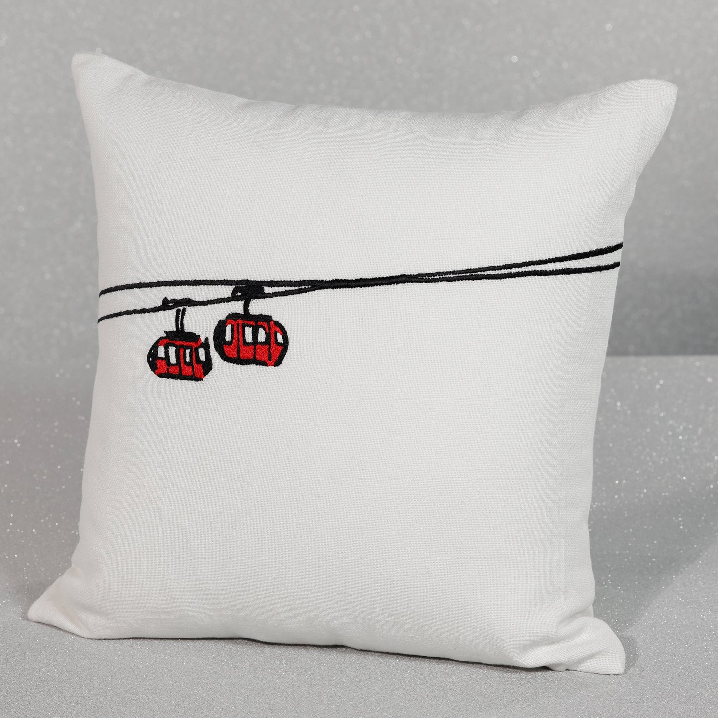 White pillow with red cable cars on a gray background