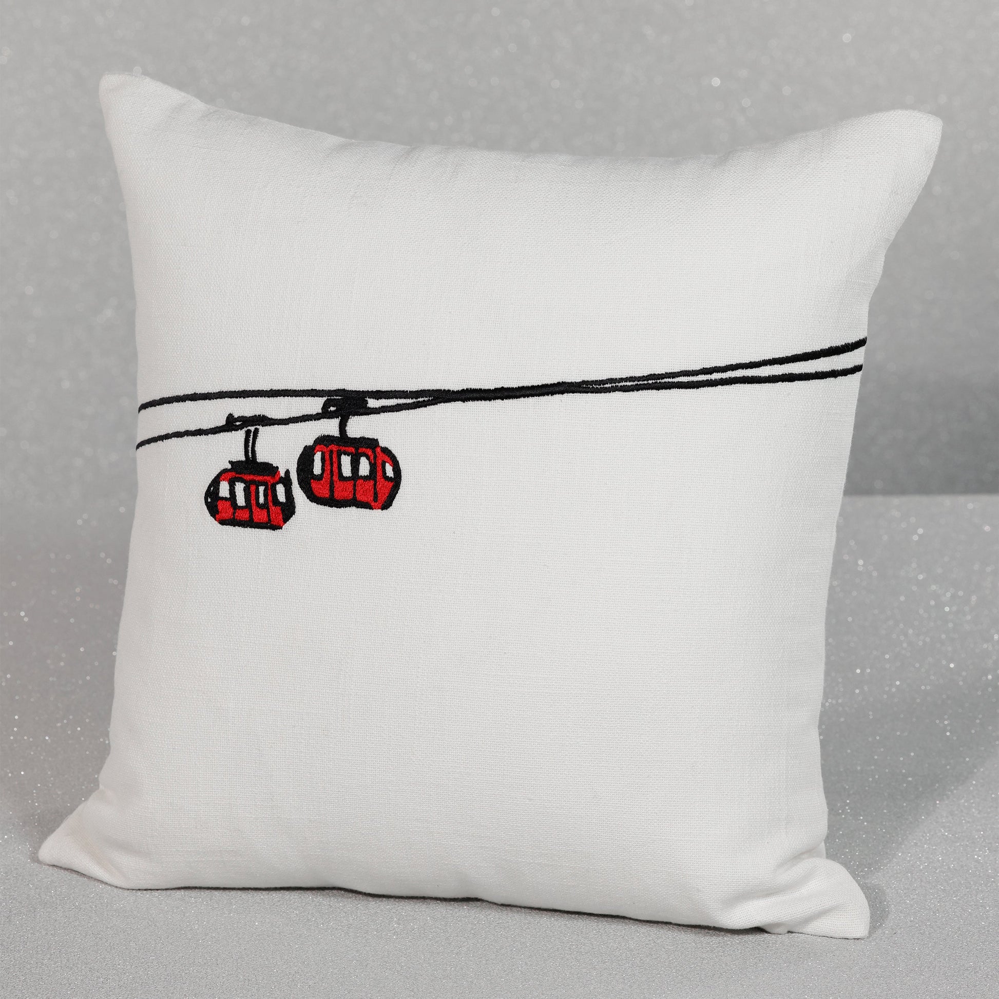 White pillow with red cable cars on a gray background