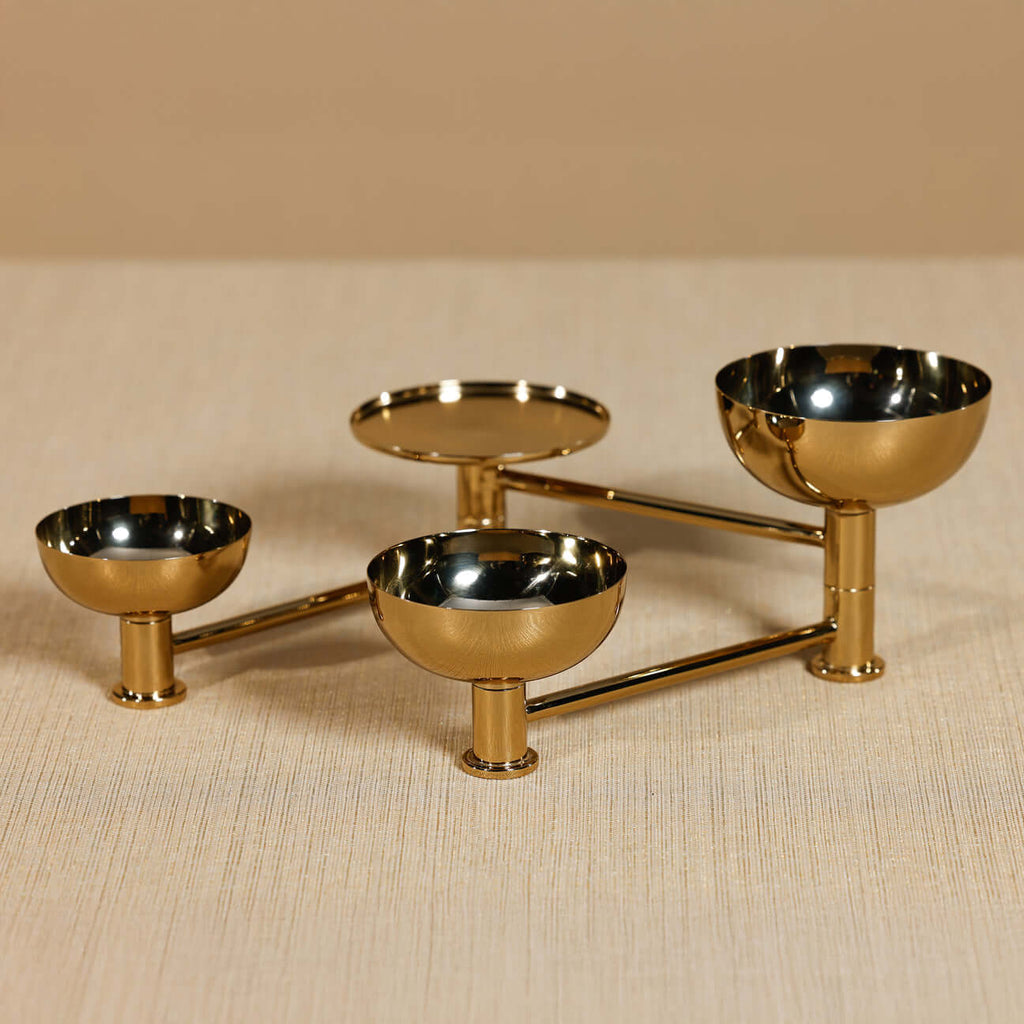 Gold metal three-tiered serving dish on a beige surface