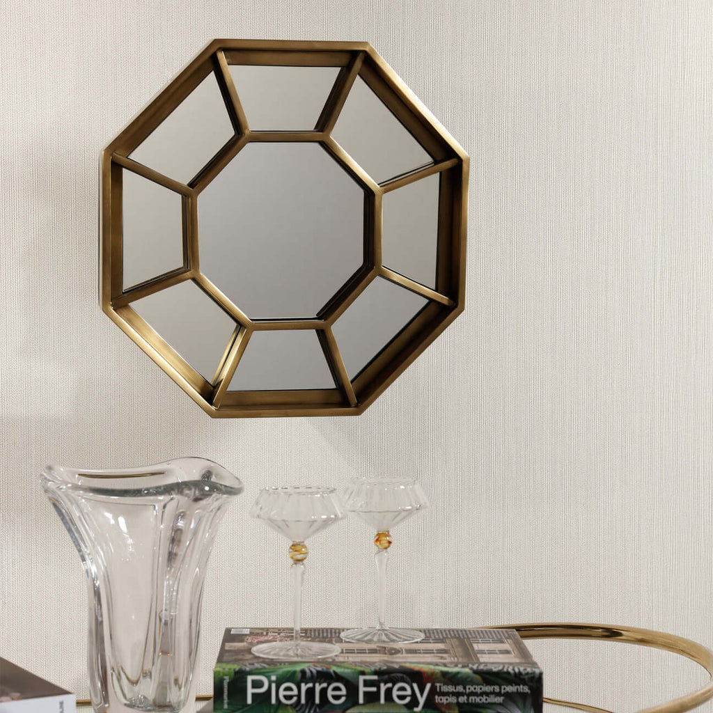 Celesta Hex Wall Mirror framed in brushed brass with geometric spoke design, reflecting light beautifully.