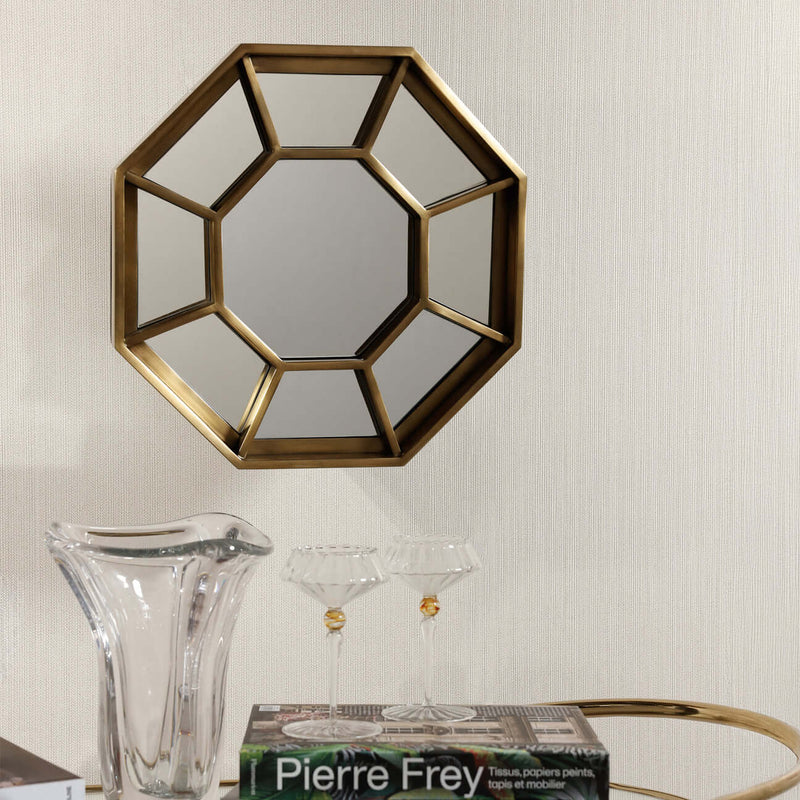 Celesta Hex Wall Mirror framed in brushed brass with geometric spoke design, reflecting light beautifully.