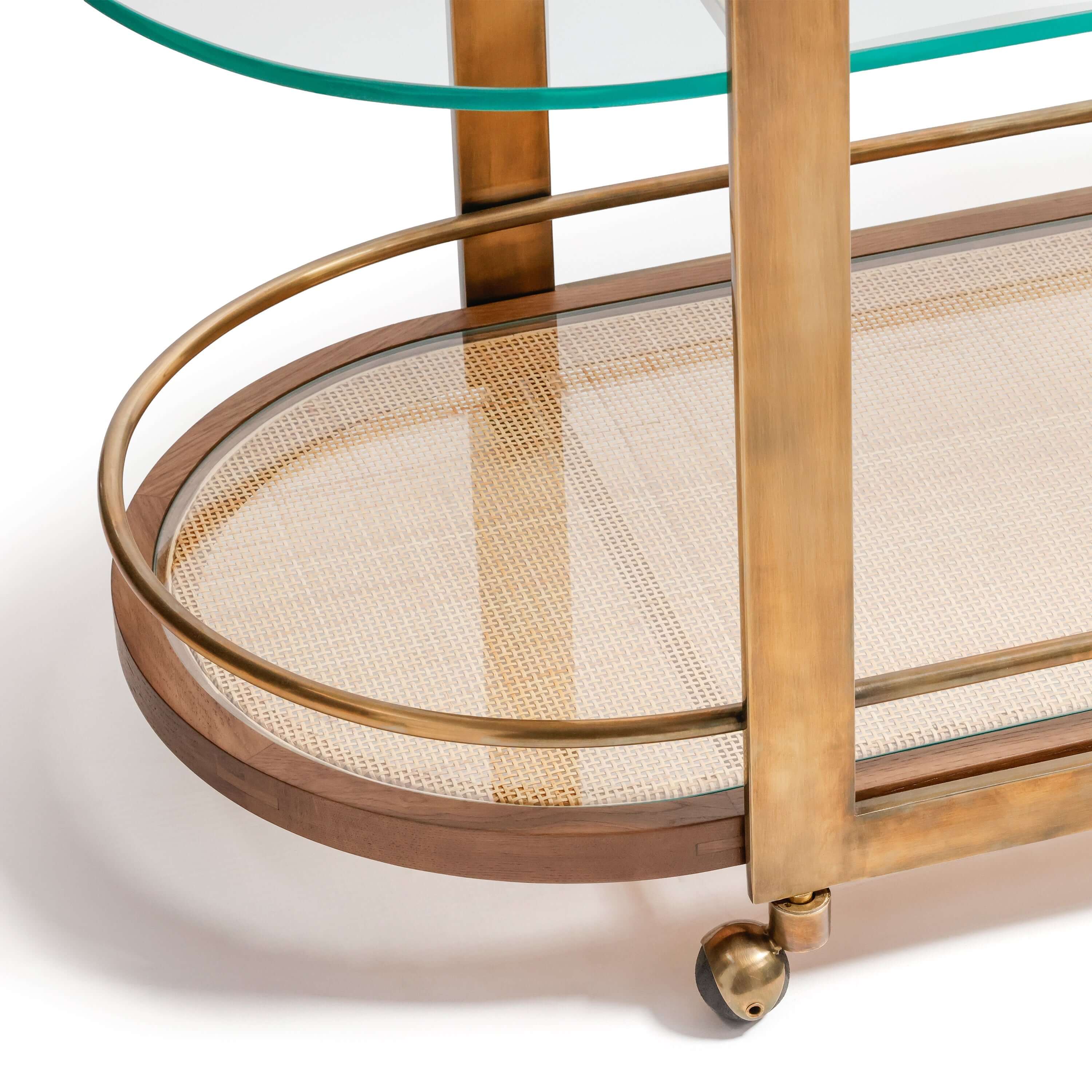Close-up of the Sloane Oak Wood Oval Bar Cart showcasing the antique brass frame and elegant glass shelves.
