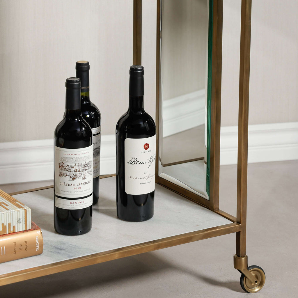 Soho Marble Bar Cart featuring brass handles and wine bottles on a stylish white marble surface.