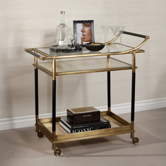 Gold and black serving cart with decorative items on a neutral background