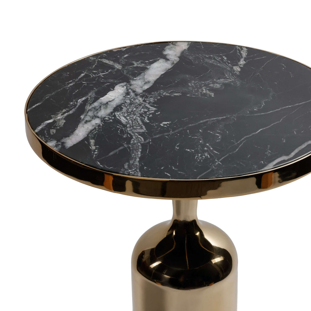 Close-up of the Nomad Table featuring a nero marquina marble top and polished gold trim.