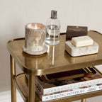 Aman Étagère showcasing elegant storage with candle, soap, and magazines on a warm antique brass table.