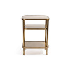 Aman Étagère, a three-tier open shelving table in warm antique brass, featuring rounded corners and cylindrical posts.