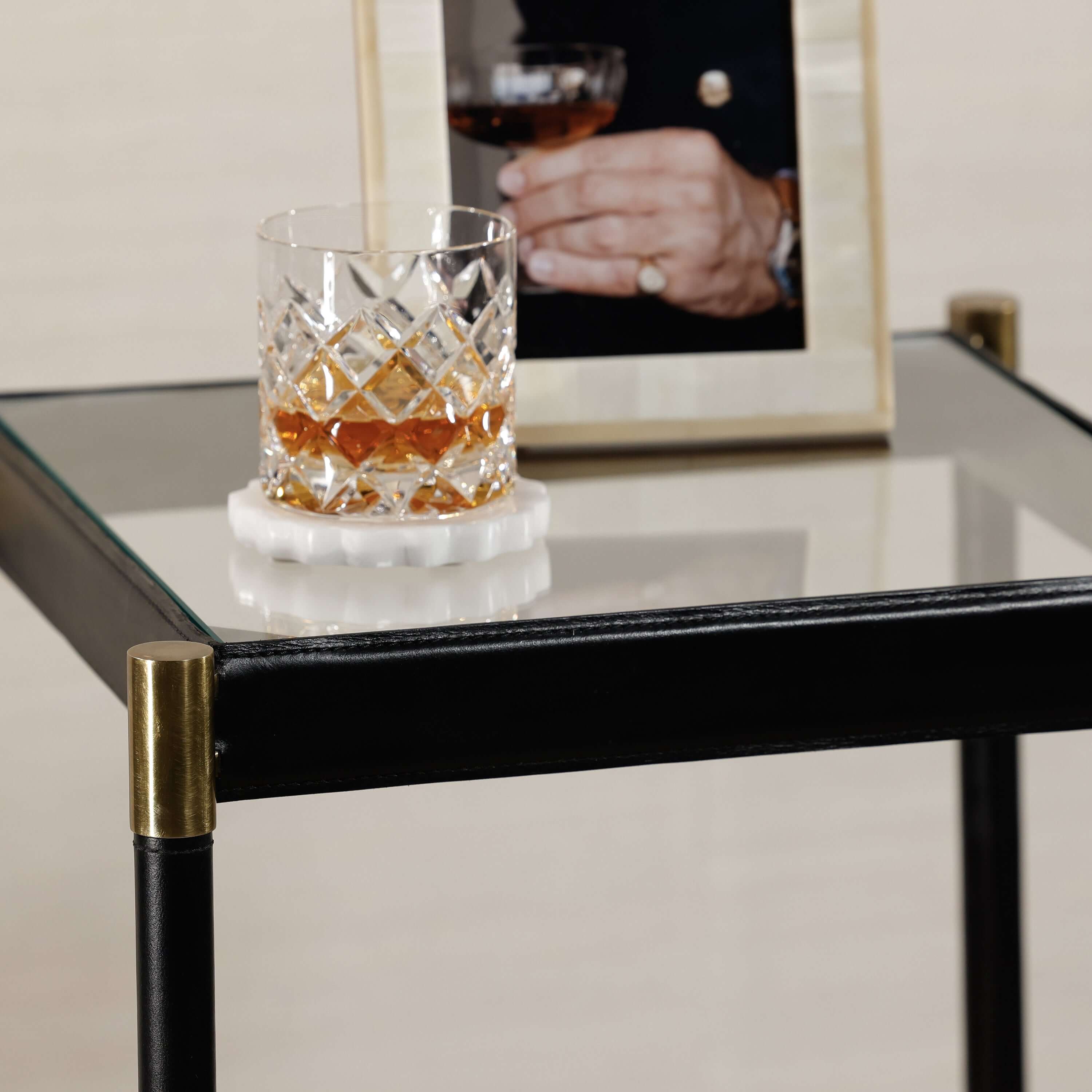 Park Lane 18 Leather Side Table featuring a glass top, leather edges, brass fittings, and a whiskey glass.