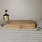 Elegant burl wood veneer Marbella Backgammon Set case with swirling grain, on a table with drinks.
