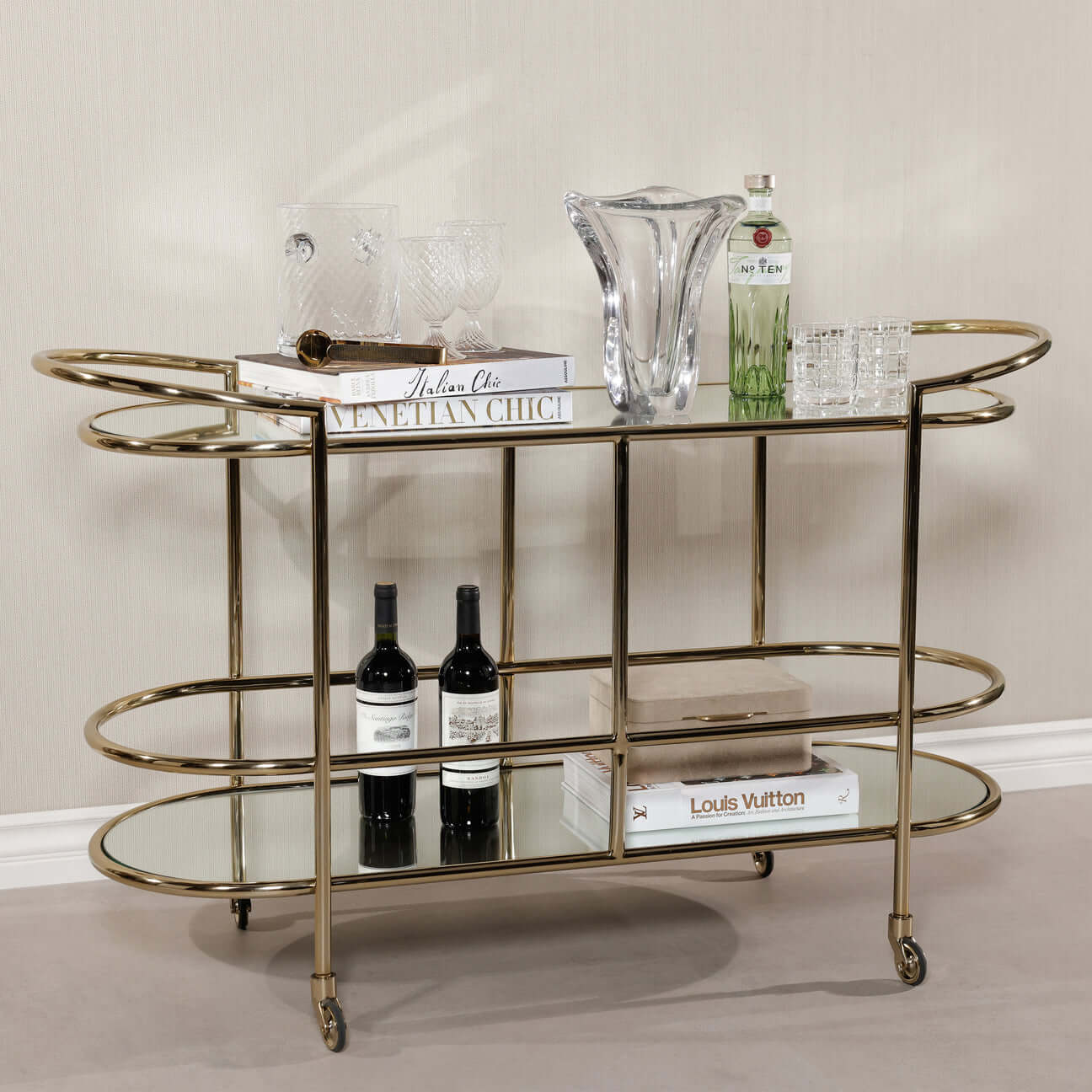 Lido Console Bar Cart featuring champagne brass frame and decorative glassware.