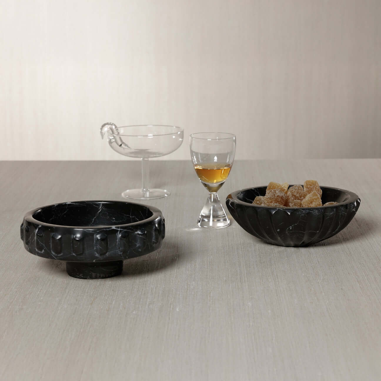 Selene Marble Bowl displayed with a clear glass, shot glass, and sugar cubes on a modern table.