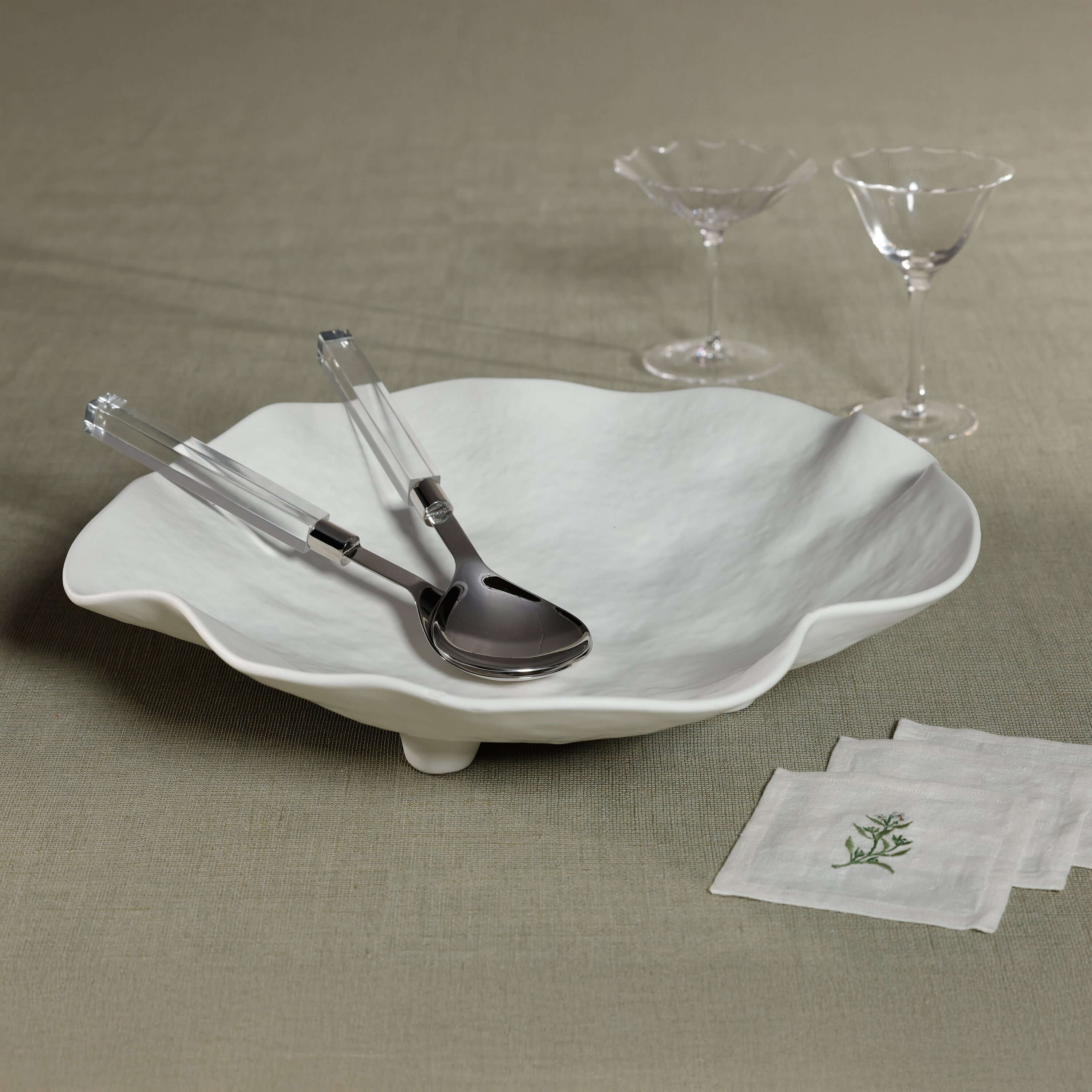 Mougins Salad Server Set with Acrylic Handle displayed with an elegant bowl and glassware on a textured tablecloth.