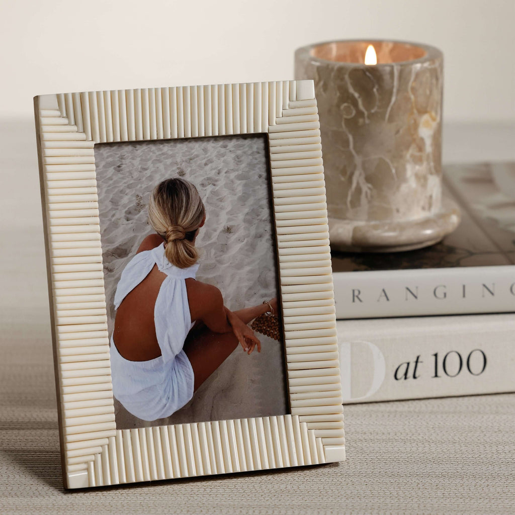 Nubia White Bone Ribbed Photo Frame showcasing a hand-carved design next to a candle and books.