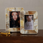 Two decorative photo frames with a woman's face on a wooden surface.