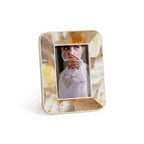 Shell-patterned photo frame with a woman holding a glass inside on a white background