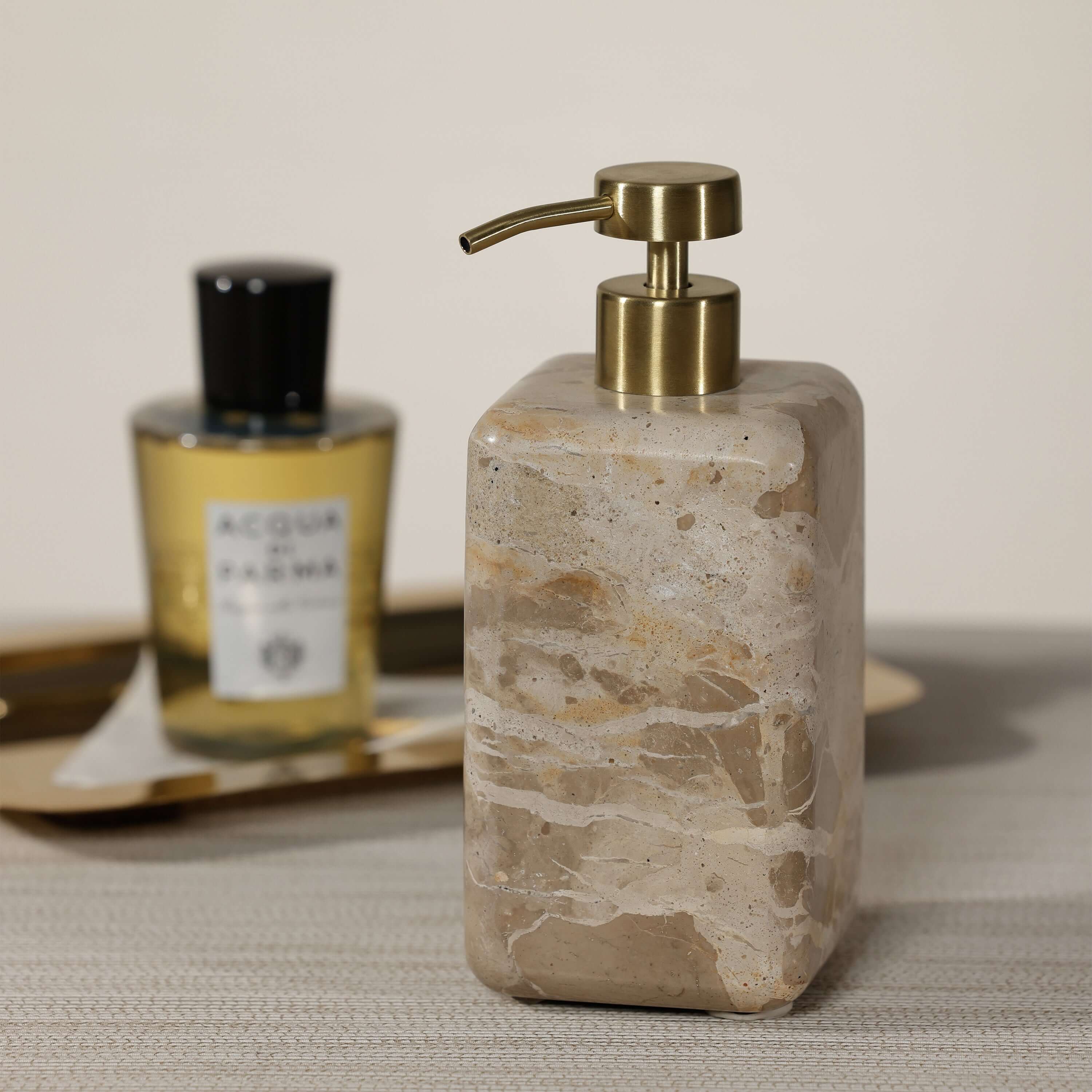 Crema Fossil Marble Bath Collection soap dispenser with a polished stone finish and gold pump on a stylish countertop.