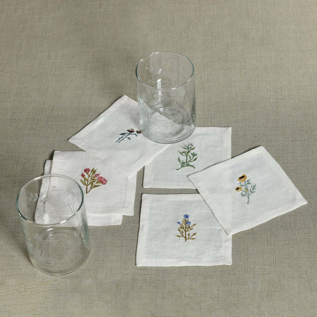Floral Linen Cocktail Napkins - 6 Assorted Designs (Set of 6) with embroidered floral motifs and glasses.