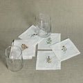 Floral Linen Cocktail Napkins - 6 Assorted Designs (Set of 6) with embroidered floral motifs and glasses.