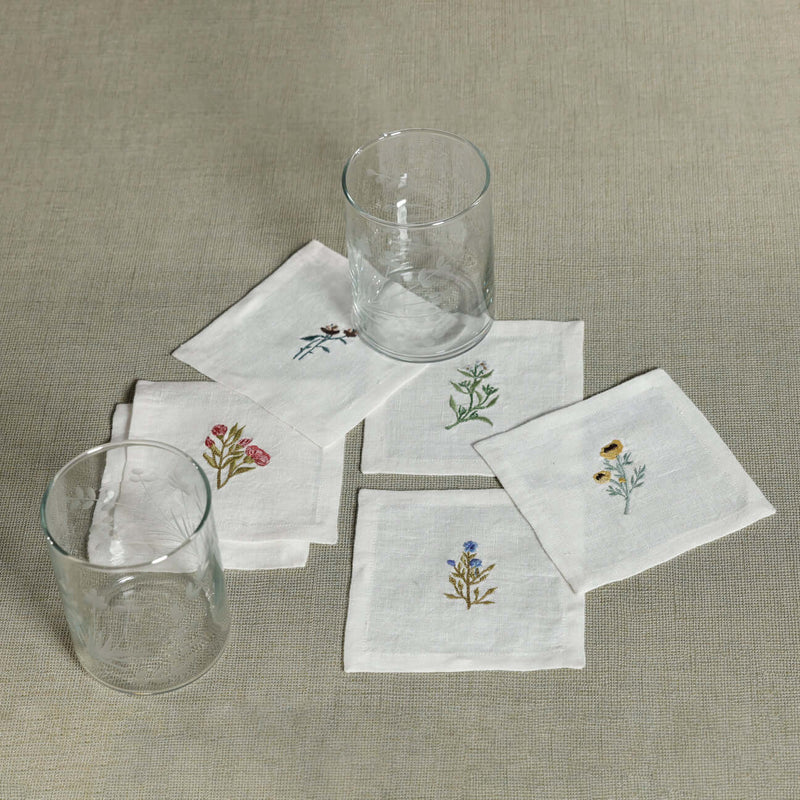 Floral Linen Cocktail Napkins - 6 Assorted Designs (Set of 6) with embroidered floral motifs and glasses.