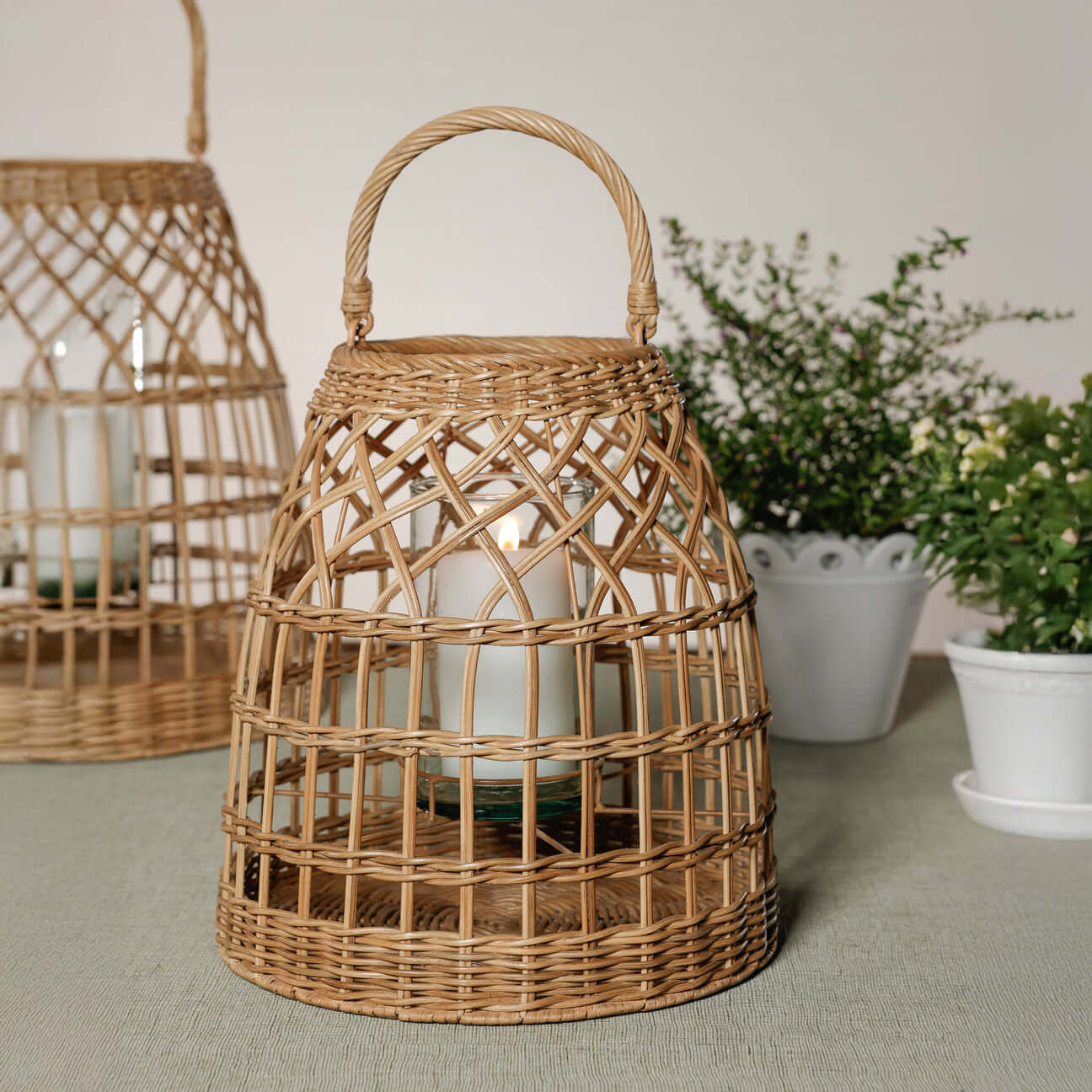 Veranda Rattan Lantern with Glass Hurricane showcasing a hand-woven design and a candle inside.