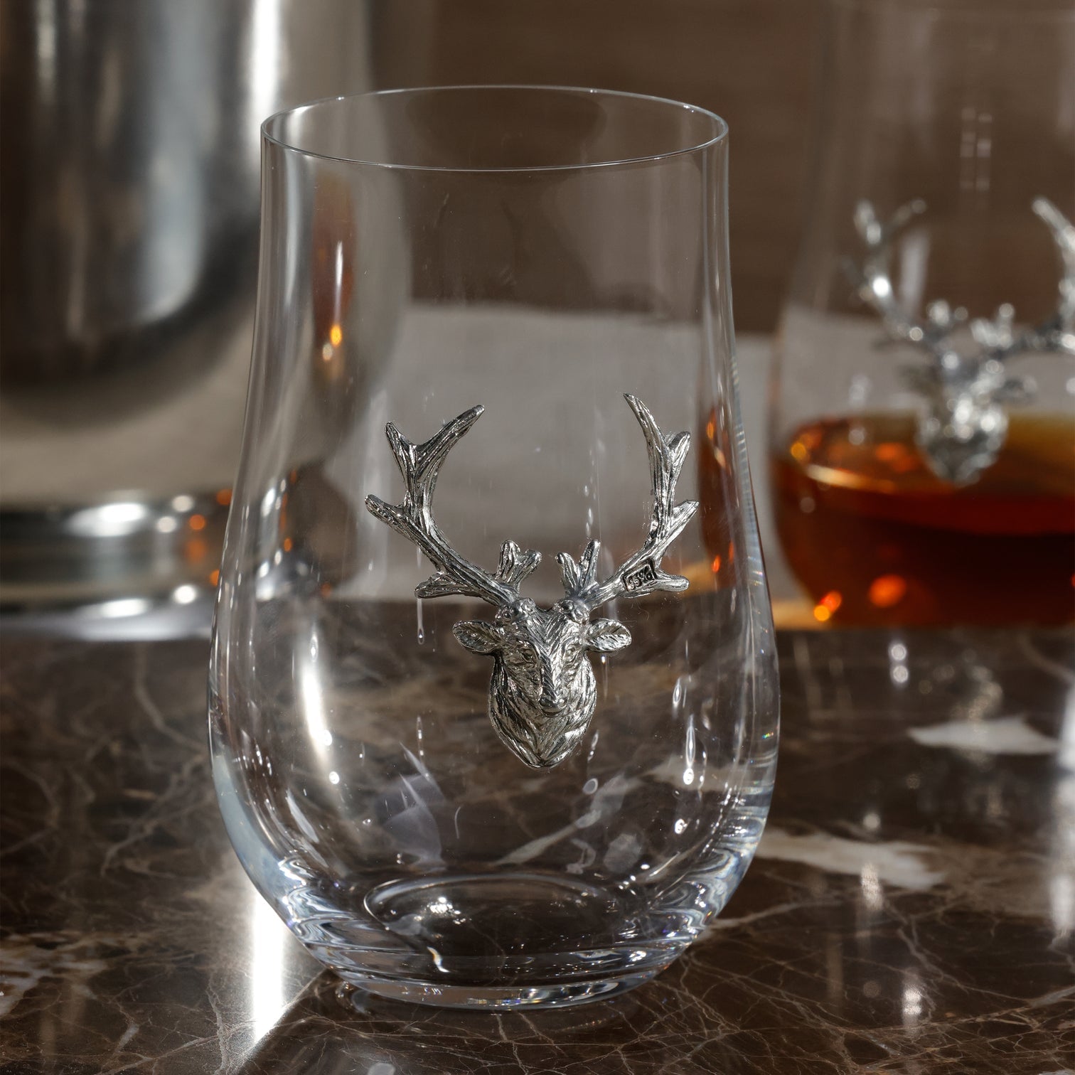 Clear glass with deer head design on a marble surface