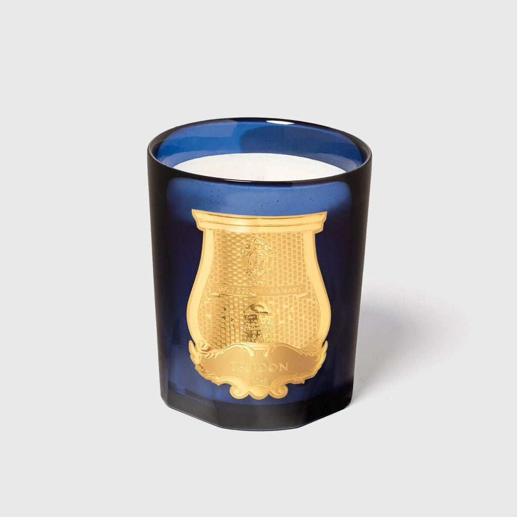 Madurai Classic Candle in an elegant blue glass container with a gold emblem.